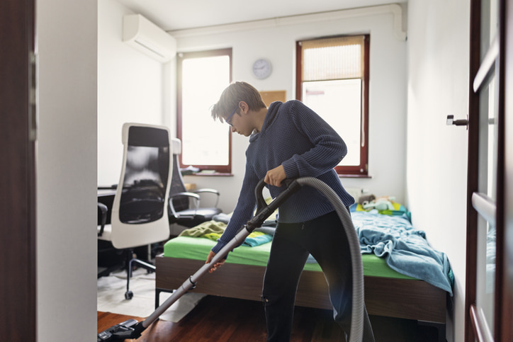 Boy vacuuming his bedroom